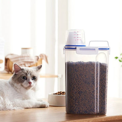 chat assis sur table avec boite à croquettes pour chat transparente