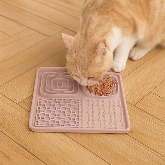 chat mangeant dans tapis de lechage compartimente rose